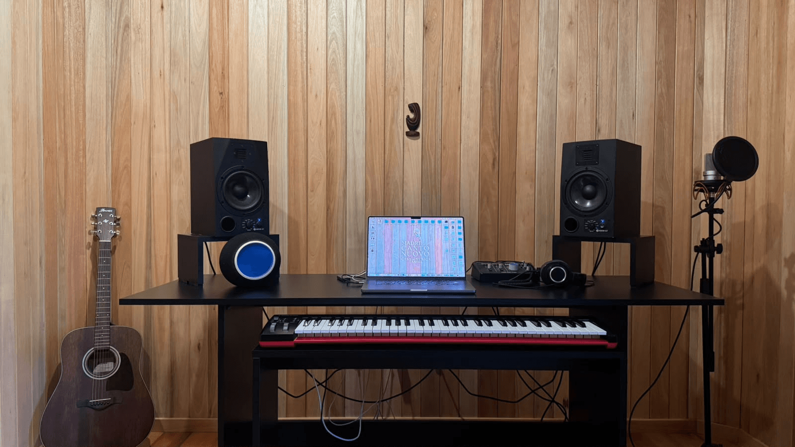 Sala del estudio Madre del Canto Nuovo: paredes de madera, monitores, teclado y micrófono